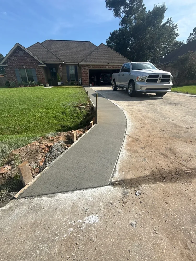 Fresh concrete driveway addition extending toward a home in Abita Springs, Louisiana.